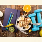 Symbolbild mit Massband, gesunder Ernährung und Hanteln im Kontext von Diäten und Gewichtsregulation.