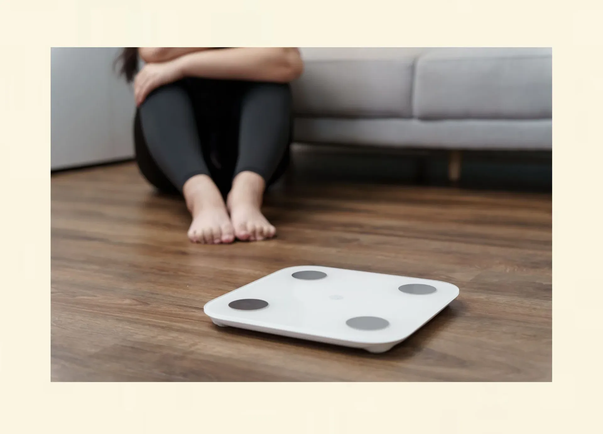 Frau sitzt neben einer Waage – symbolische Darstellung von Gewichtsschwankungen beim Jo-Jo-Effekt.