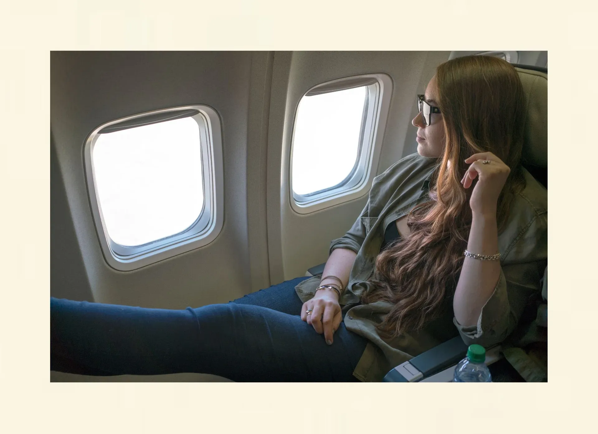 Nachdenkliche Frau schaut aus dem Flugzeugfenster – Verstand reicht bei Flugangst oft nicht aus