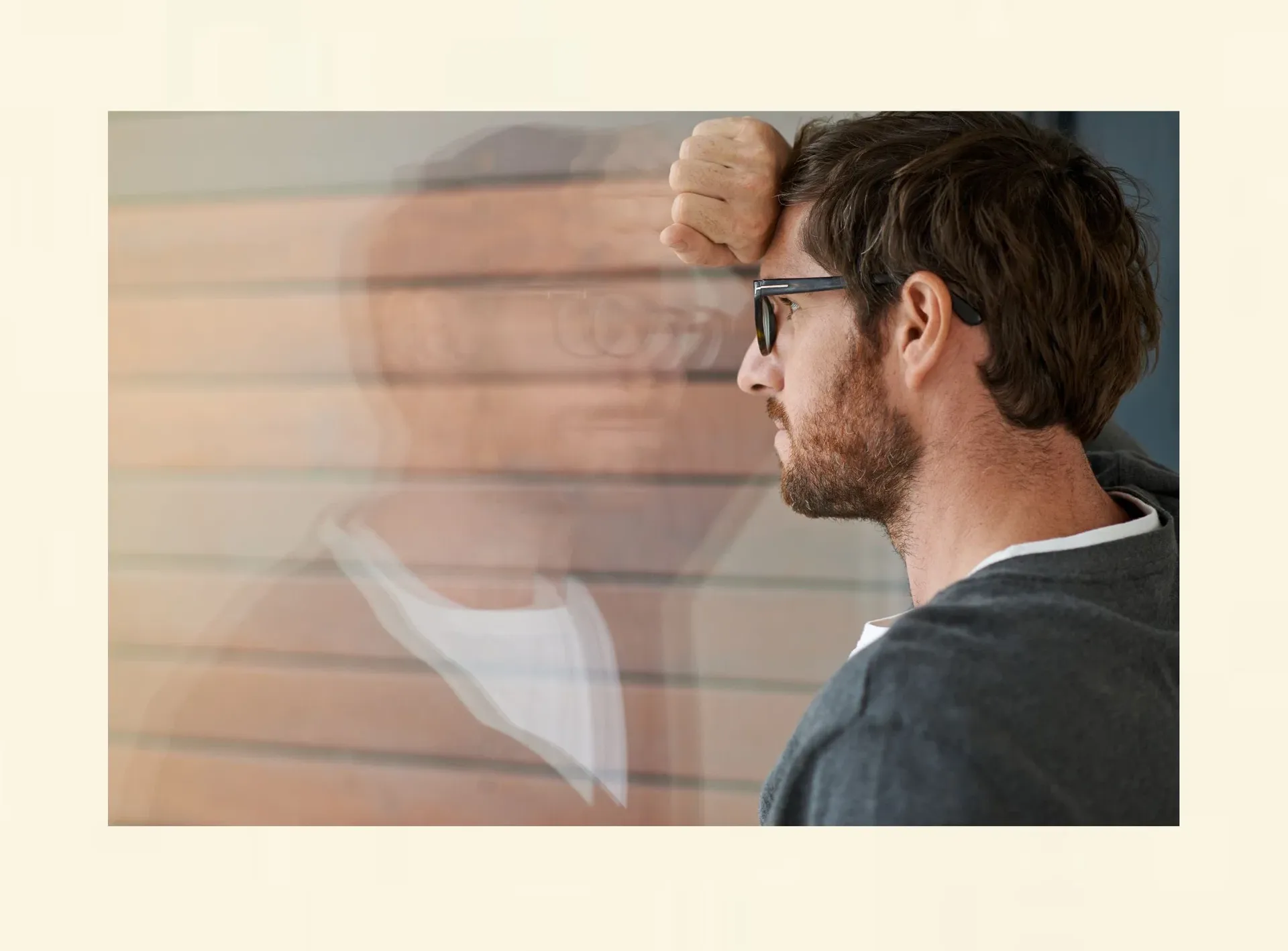 Nachdenklicher Mann am Fenster als Symbol für tieferliegende Verlustangst und innere Unsicherheit